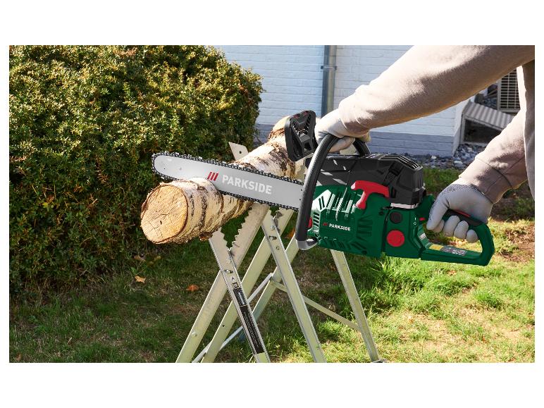 Mann in Handschuhen schneidet Holz mit einer Kettensäge auf einem Sägebock.