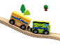 Holzspielzeugeisenbahn mit zwei Waggons auf einer ansteigenden Schiene, mit Bäumen im Hintergrund.