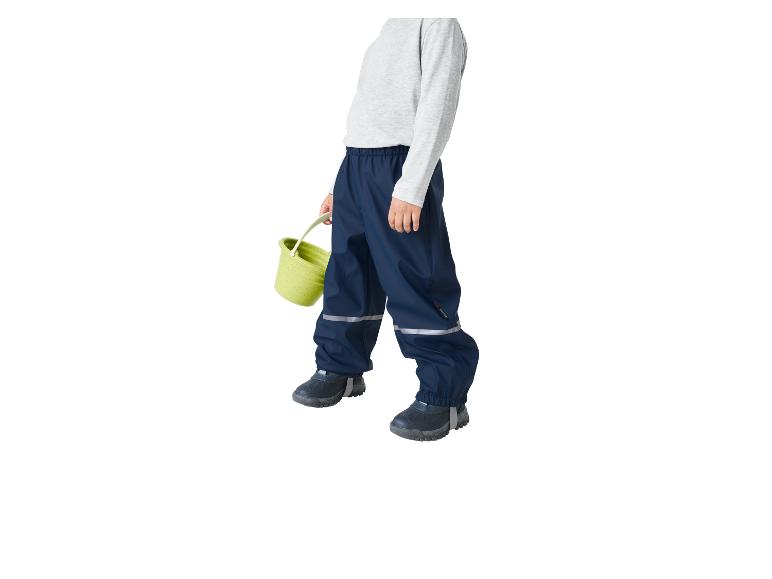 Kind in dunkelblauer Regenhose und grauem Shirt, hält einen grünen Eimer.