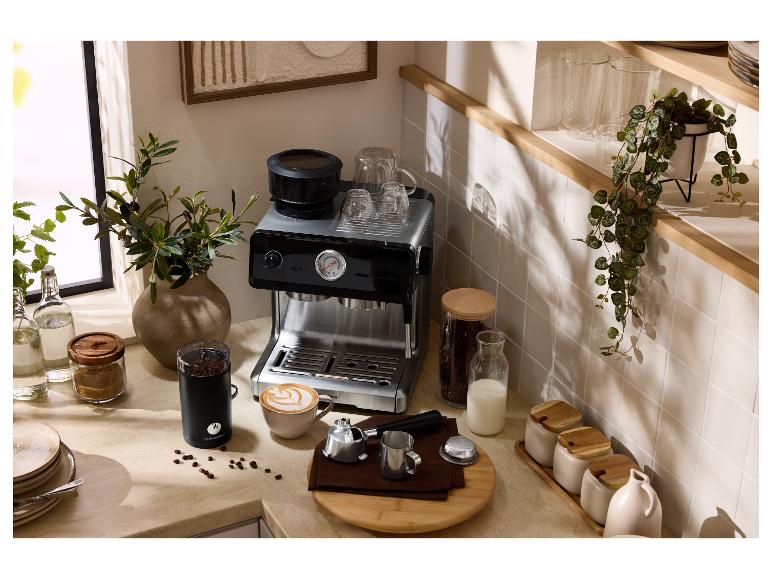 Küchenarbeitsplatte mit Espressomaschine, Kaffeemühle, Tassen und Kaffeebohnen.