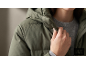 Nahaufnahme einer Frau in einer olivgrünen Daunenjacke und einem grauen Pullover.