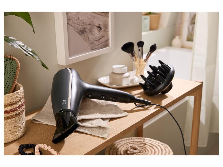 Haartrockner und Diffusor auf einem Holztisch mit Beauty-Accessoires im Badezimmer.