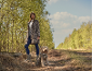 Frau in Leopardenmuster-Jacke und Hund in passender Weste auf einem Waldweg.