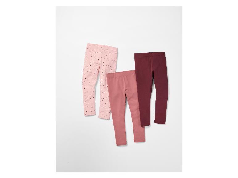 Drei Kinderleggings in Rosa- und Burgunder-Tönen.
