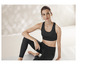 Eine Frau trägt einen schwarzen Sport-BH und Leggings.
