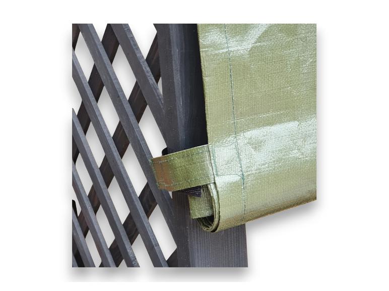 Grüne Plane an einem dunklen Holzspalier befestigt