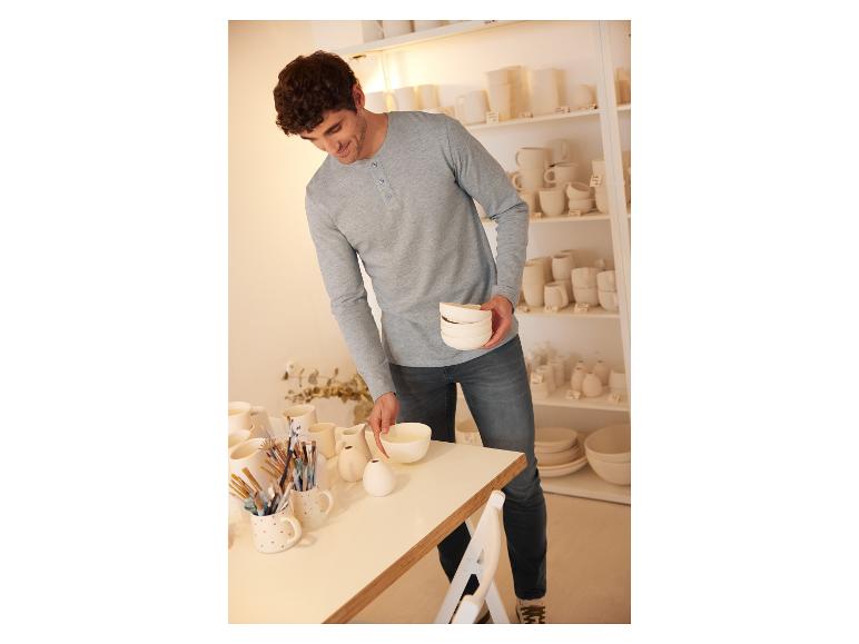 Ein Mann betrachtet weiße Keramik-Schalen und Tassen in einem Geschäft.