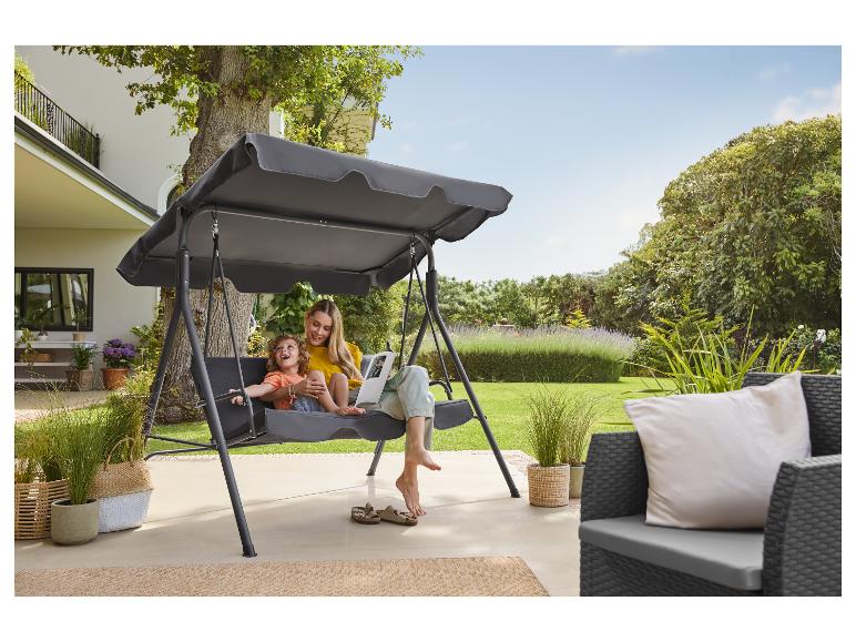 Mutter und Kind schaukeln auf einer Gartenschaukel mit Überdachung auf einer Terrasse.