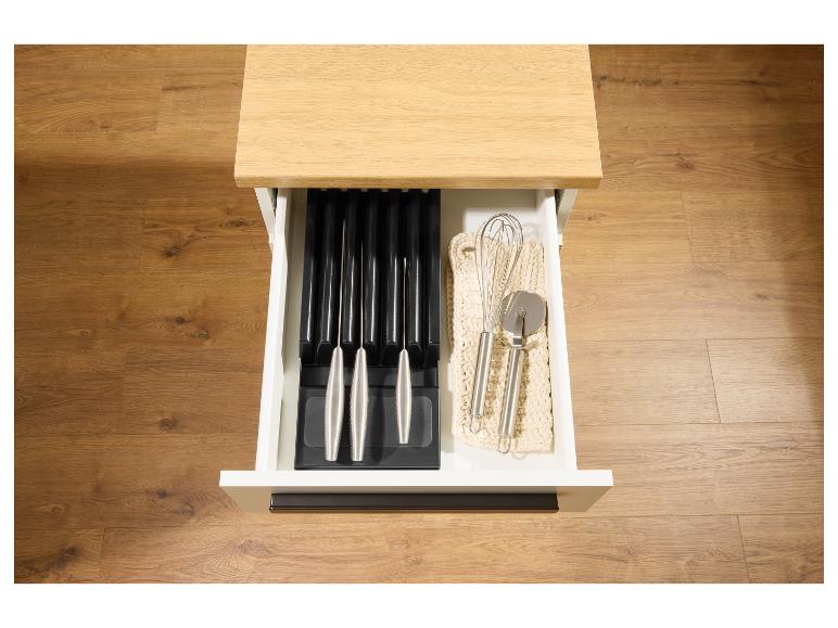 Geöffnete Küchenschublade mit Messerblock und Küchenutensilien wie Schneebesen und Pizzaschneider.