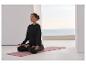 Frau meditiert auf einer Yogamatte, trägt schwarzes Sweatshirt und Hose.