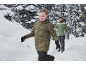 Junge in grüner Steppjacke und Mann in grüner Outdoor-Jacke rennen im Schnee.