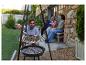 Mann grillt Meeresfrüchte auf einem Dreibein-Grill mit Freunden im Hintergrund.