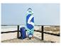 Stand-Up-Paddleboard und Rucksack auf einer Holzterrasse am Meer.