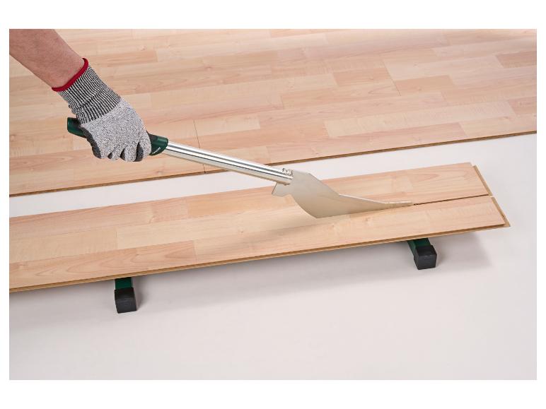 Ein Arbeiter schneidet eine Laminatdiele mit einem Laminatschneider.