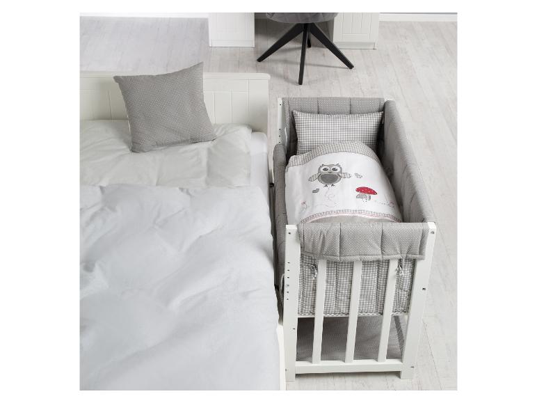 Weißes Babybett mit Eulenbettwäsche und Einzelbett mit grauem Kissen.