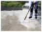 Eine Person reinigt mit einem Parkside Hochdruckreiniger eine Terrasse.