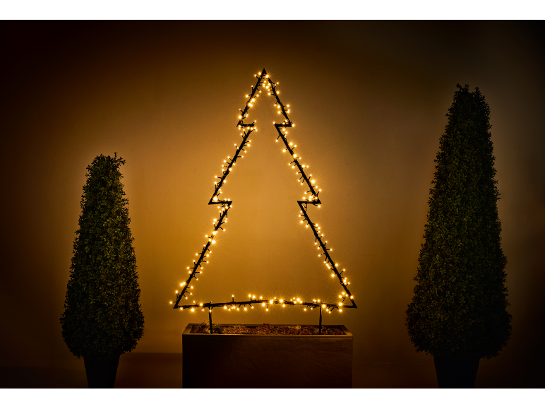 Beleuchtete Weihnachtsbaum-Silhouette mit zwei Topiary-Bäumen in Töpfen.