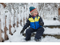 Lächelndes Kind in Skijacke und Schneehose sitzt auf verschneiten Stufen.
