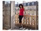 Frau in rotem Tanktop und schwarzen Capri-Leggings auf einem Balkon mit Steinbalustrade.