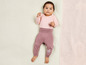 Ein Baby in einem rosa Langarmshirt und lila Hosen mit Blumenmuster.