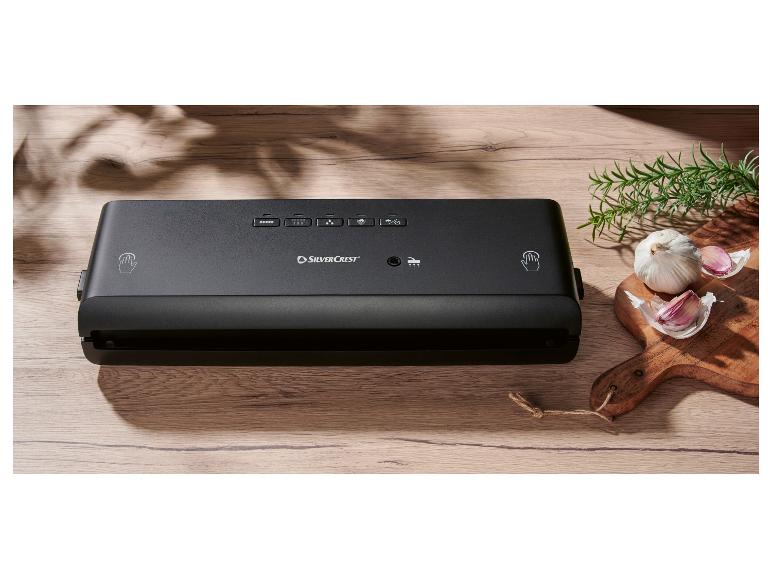 SilverCrest Vakuumiergerät auf einem Holztisch, mit Knoblauch und Rosmarin.