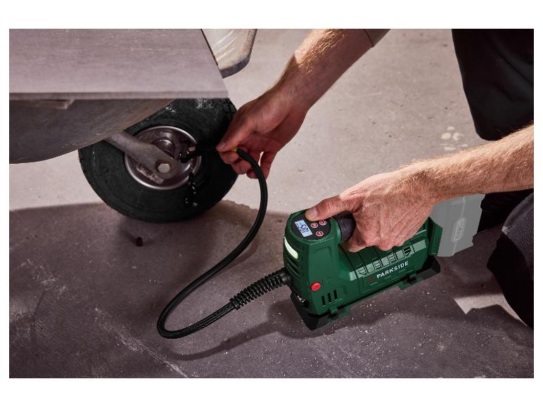 Ein Mann pumpt ein Schubkarrenrad mit einem tragbaren Parkside Kompressor auf.