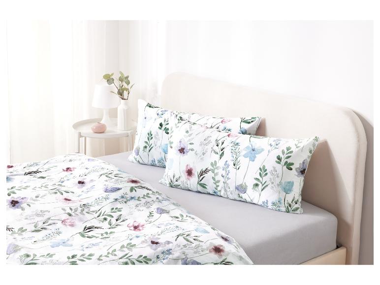 Ein Bett mit einem weißen Bettbezug mit Blumendruck und zwei passenden Kissen.