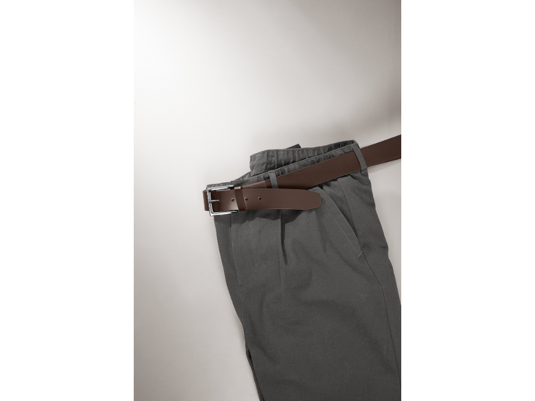 Graue Hose mit einem braunen Gürtel auf hellem Hintergrund.