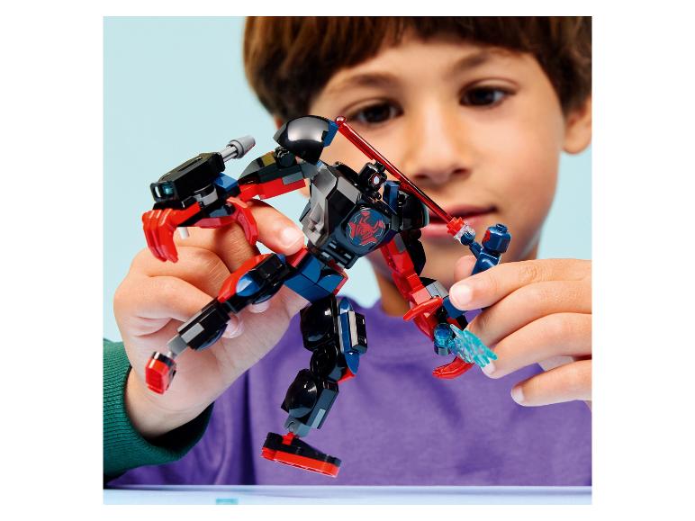 Ein Kind spielt mit einem schwarz-roten Roboterspielzeug und einer kleinen blauen Figur.