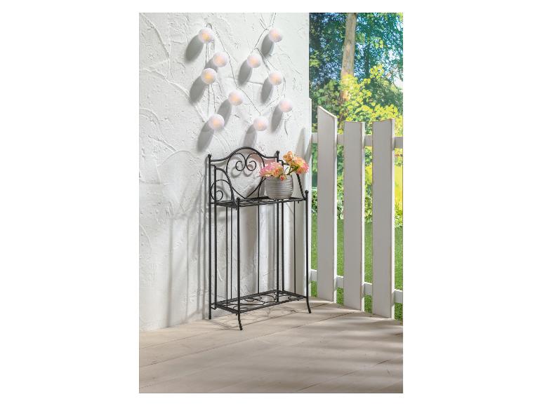 Weiße Baumwolllichter auf einem Metall-Pflanzenständer mit Blumen.