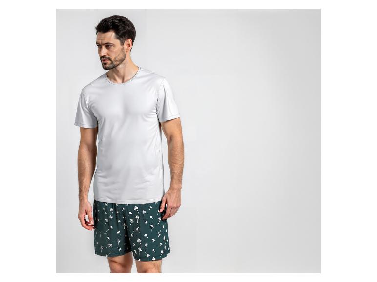 Mann in weißem T-Shirt und Badeshorts mit Palmenmuster.