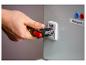 Hand benutzt ein Multitool, um ein Schloss an einer grauen Box mit Text zu öffnen.