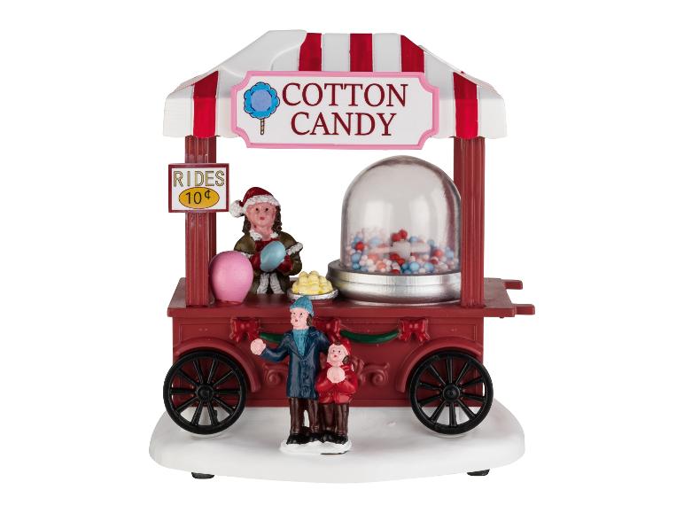 Ein festlicher Zuckerwattewagen mit Figuren, einem „Rides 10¢“-Schild und einem Süßigkeitenspender.