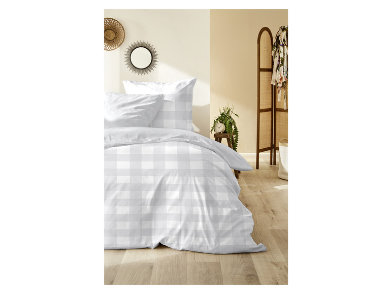 Eine weiße Bettwäsche mit Karomuster auf einem Holzboden.