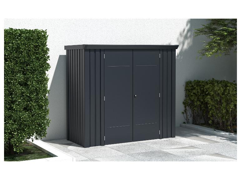 Dunkelgrauer Gartenschrank mit Doppeltüren, auf einer Terrasse neben einem grünen Strauch.