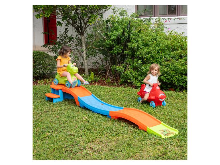 Zwei Mädchen spielen draußen mit einer Spielzeug-Achterbahnrutsche und einem Spielzeugauto.