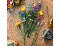 Bunter Blumenstrauß aus Bausteinen auf einem geflochtenen Teppich mit Gartenzubehör.