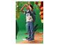 Junge in bedrucktem T-Shirt, Jeans und blauen Turnschuhen, schaut durch ein Spielzeugfernglas.