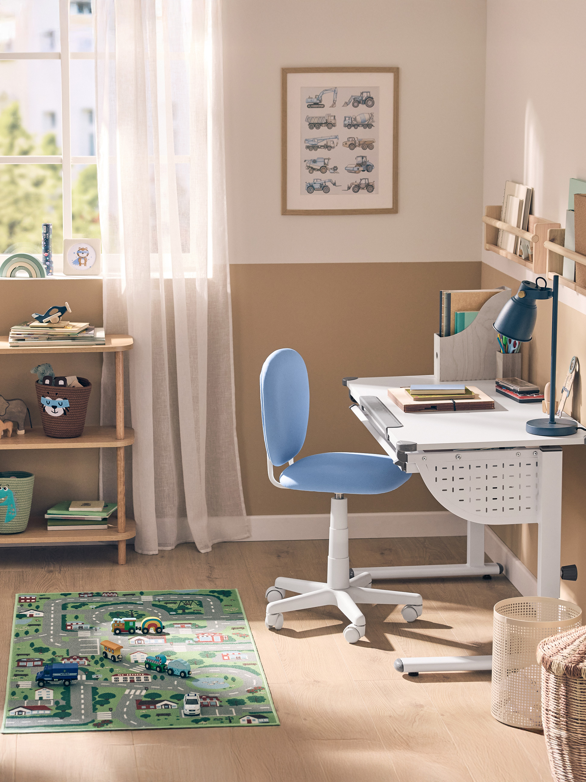 Kinderzimmer mit weißem Schreibtisch, blauem Stuhl, Holzregal und Spielteppich.