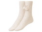 Zwei Paar weiße Wollsocken mit Bommeln.