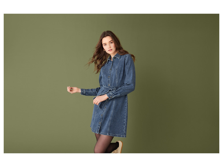 Eine Frau trägt ein langes Jeanskleid.