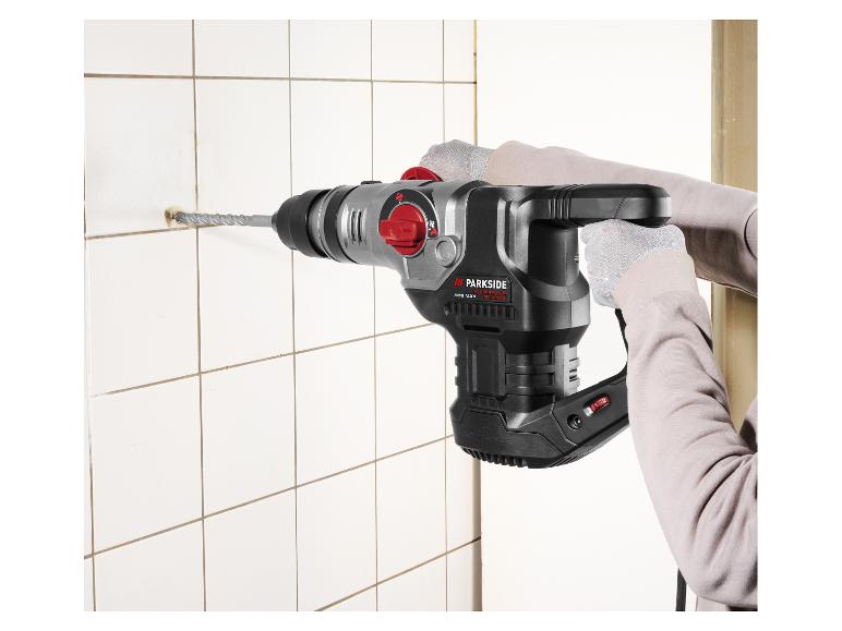 Person bohrt ein Loch in eine weiße Fliese mit einem Parkside Performance SDS Max Bohrhammer.