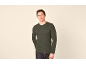 Mann in grünem Langarmshirt mit Knöpfen und Tasche, posiert vor hellem Hintergrund.