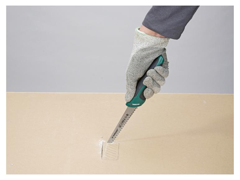 Behandschuhte Hand schneidet Holz mit einer Parkside Handsäge