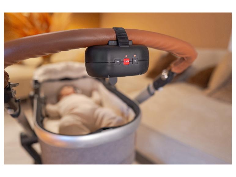 Ein schwarzes ZAZU-Gerät ist am braunen Griff eines Kinderwagens mit Baby befestigt.