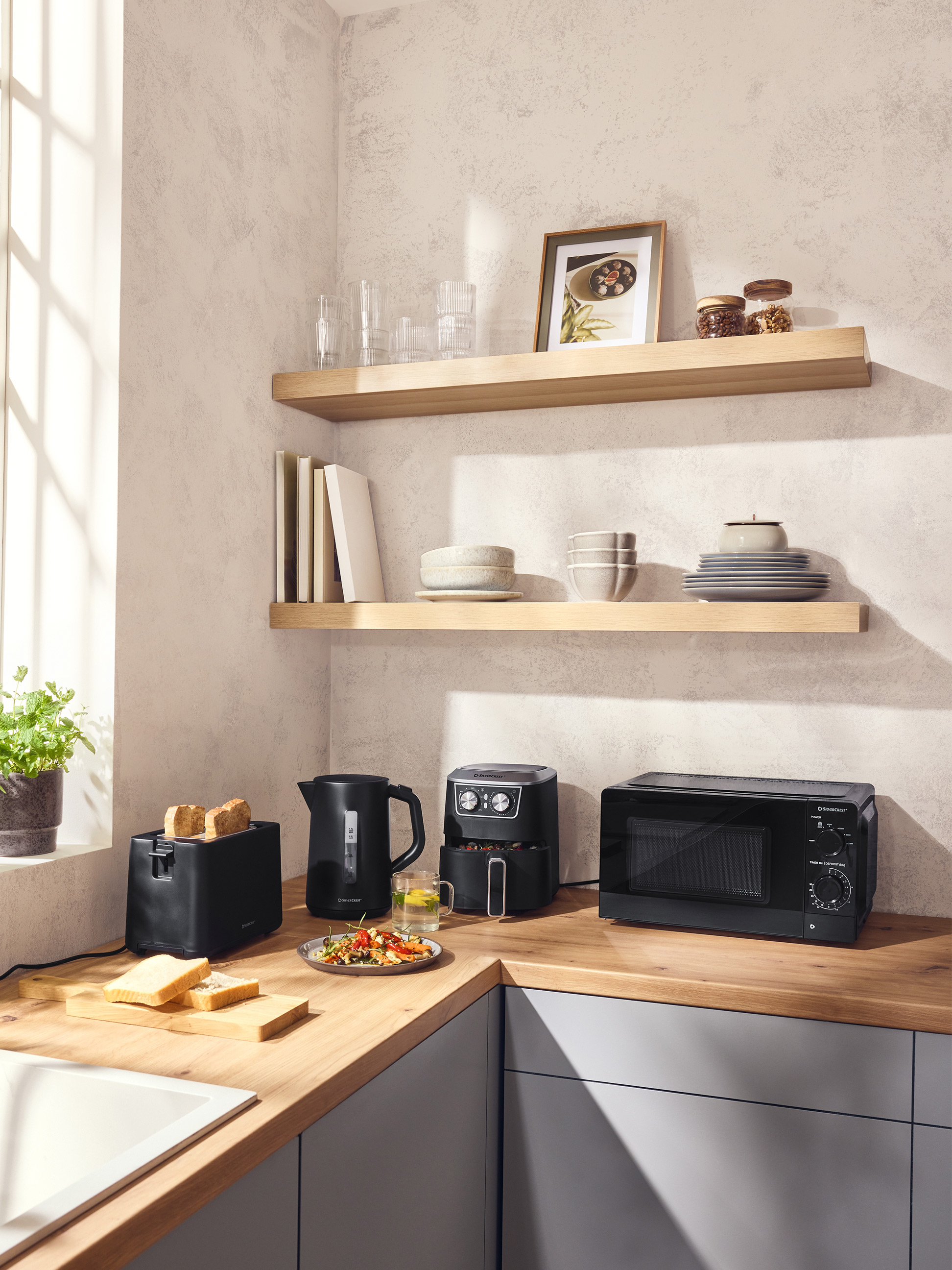 Moderne Küche mit schwarzem Toaster, Wasserkocher, Heißluftfritteuse und Mikrowelle auf einer Holztheke.