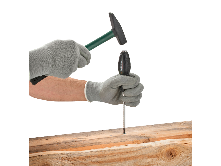 Eine Person mit Handschuhen schlägt mit einem Hammer auf einen Schraubendreher in einem Holzbalken.