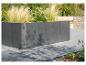 Dunkelgraues Betonblock-Pflanzgefäß mit Ziergräsern und Blumen.