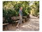 Frau in blauem Strick-T-Shirt und grauer Jogginghose geht in einem Park spazieren.