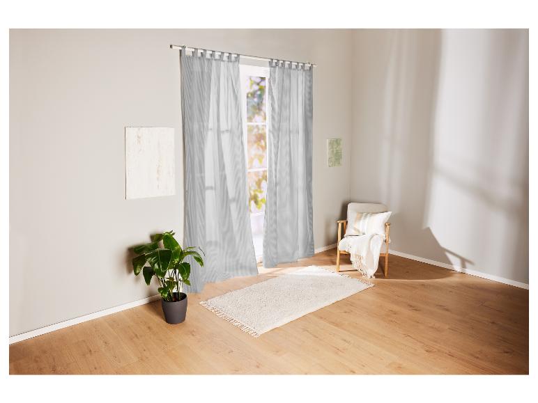 Graue gestreifte Vorhänge, ein weißer Teppich und ein Holzstuhl in einem hellen Raum.